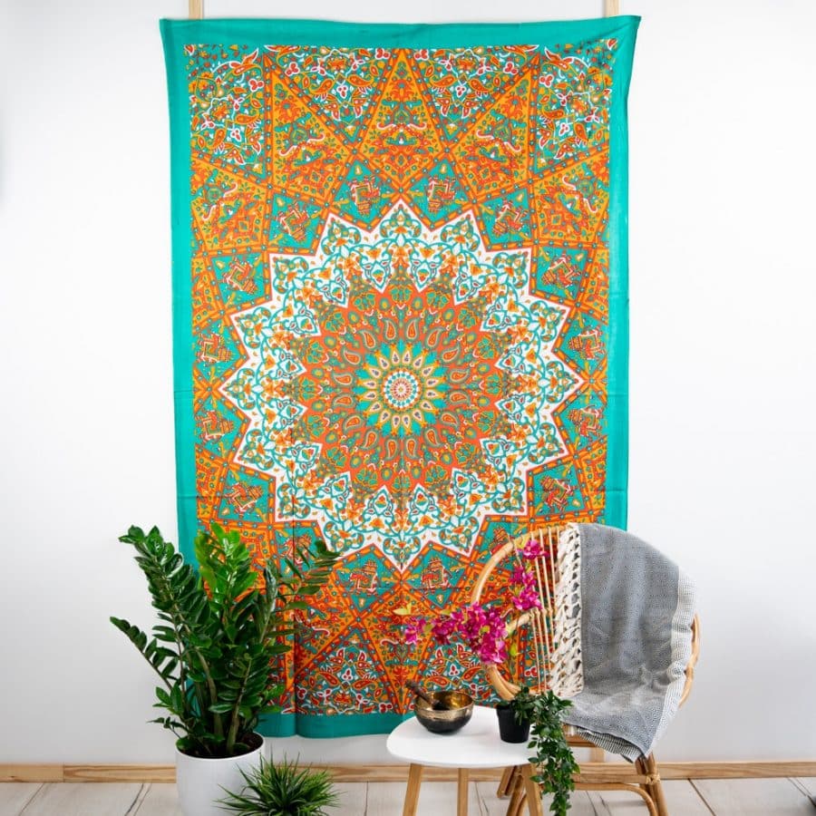 tapiz pared mandala verde con naranja y delante unas plantas y silla