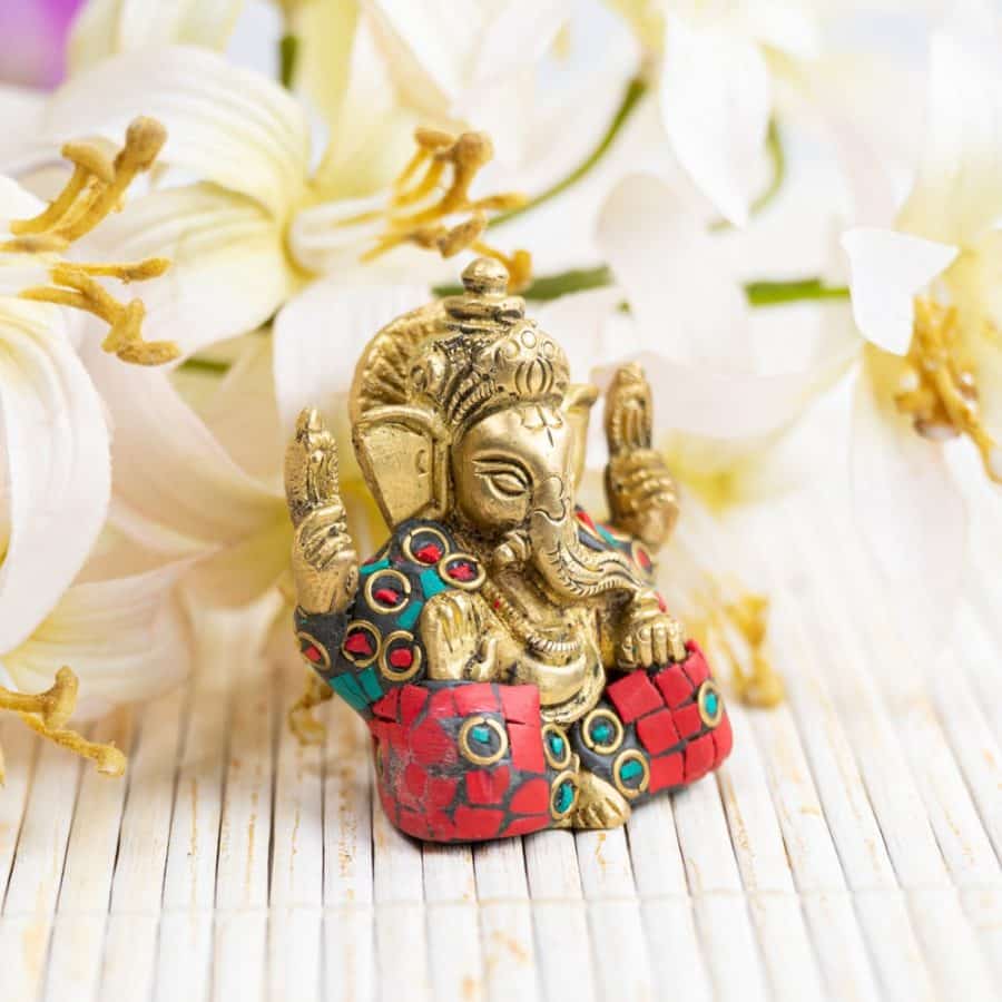 estatua ganesha dorada con detalles verdes y rojos