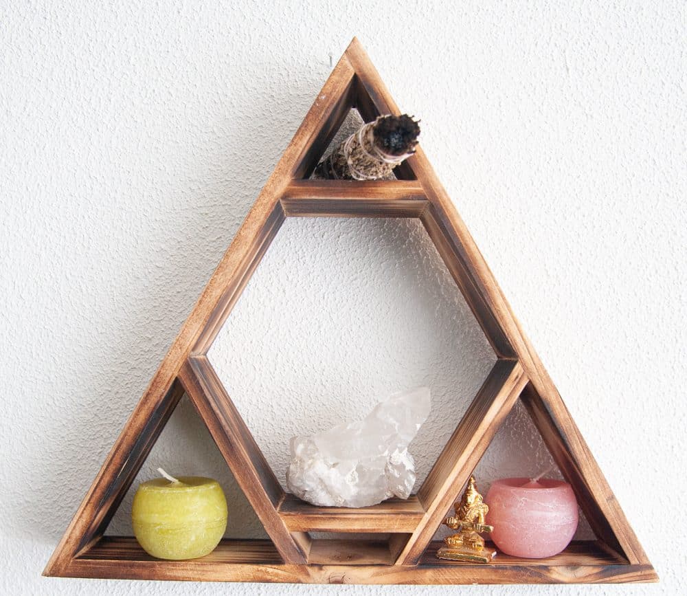 estanterilla en forma de triángulo con velas, smudge y cristal de roca. blog cómo hacer velas